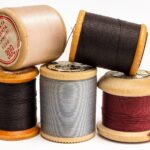 Garnrollen aus Holz mit Nähgarn in Beige, Rot, Grau und Schwarz