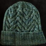 Grün melierte, handgestrickte Mütze mit Zopfmuster und Umschlag