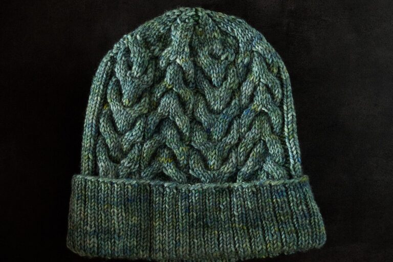 Grün melierte, handgestrickte Mütze mit Zopfmuster und Umschlag