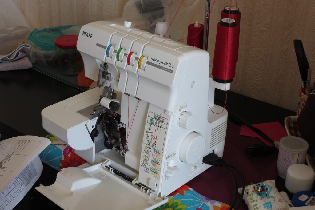 Overlock-Nähmaschine mit farbig gekennzeichneten Fadenwegen auf einem Tisch