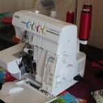 Overlock-Nähmaschine mit farbig gekennzeichneten Fadenwegen auf einem Tisch