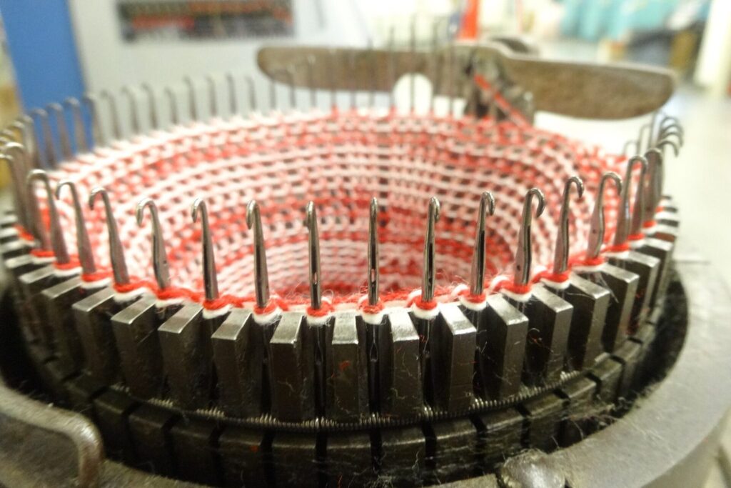 Nahaufnahme einer runden Strickmaschine mit roter Wolle