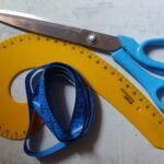 Schneiderschere, Maßband und Kurvenlineal auf weißem Untergrund