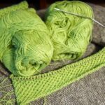 Grüne Merinowolle mit Rundstricknadel und angefangenem Strickstück